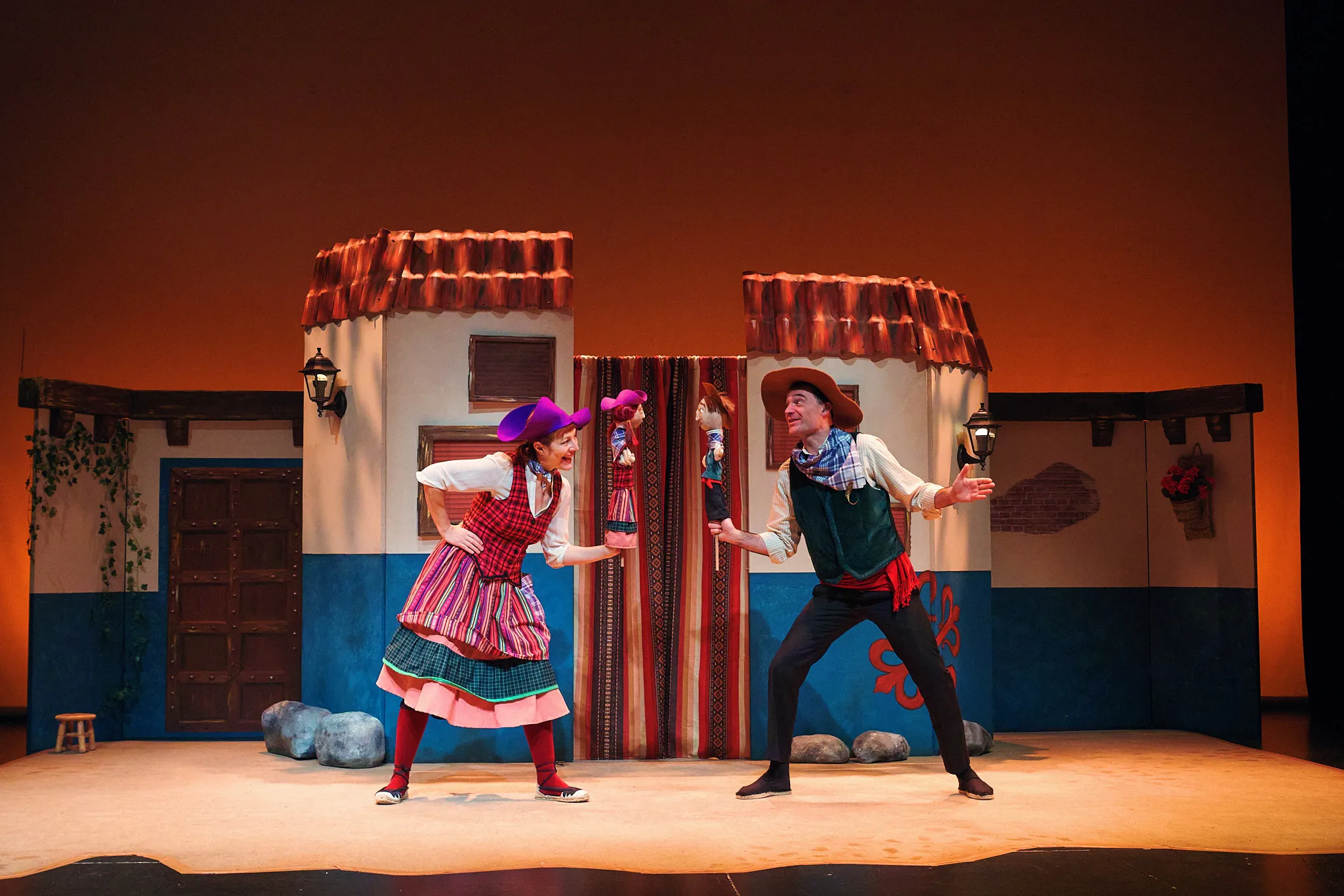 Ana Torres Lara y Javier Jiménez en escena ante dos casas blancas y azules de pueblo manchego