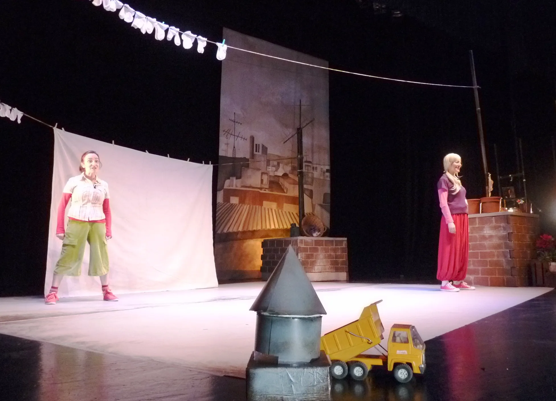 Dos actrices en escena en Sie7e pétalos, con un camión de juguete en primer plano