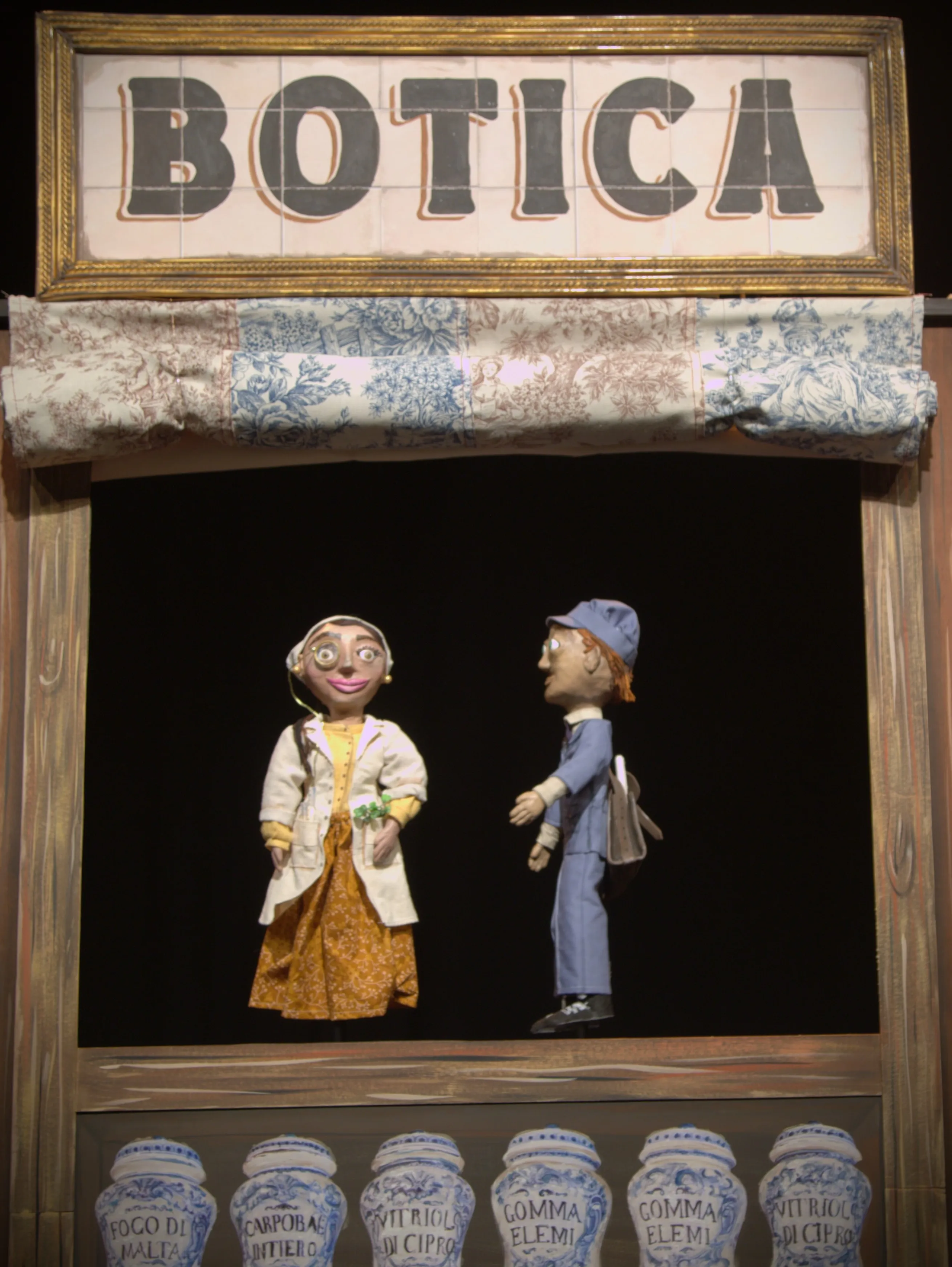 Los títeres de Matilde, la boticaria, y Baldomero, el cartero, en la ventana de la botica
